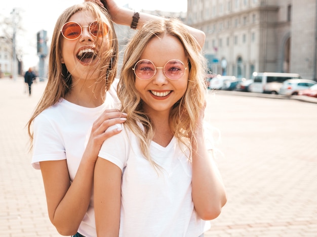 Bezpłatne zdjęcie portret dwóch młodych pięknych blond uśmiechnięte dziewczyny hipster w modne letnie białe ubrania t-shirt. .