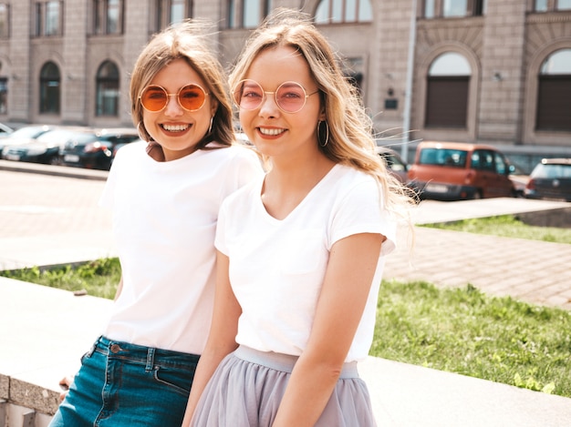 Bezpłatne zdjęcie portret dwóch młodych pięknych blond uśmiechnięte dziewczyny hipster w modne letnie białe ubrania t-shirt. .