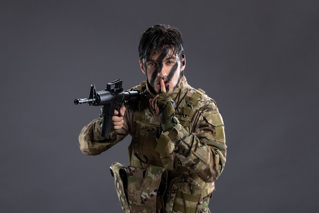 Portret dzielnego żołnierza w kamuflażu podczas operacji na ciemnej ścianie