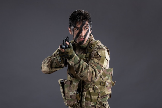 Portret dzielnego żołnierza w kamuflażu z karabinem maszynowym na ciemnej ścianie