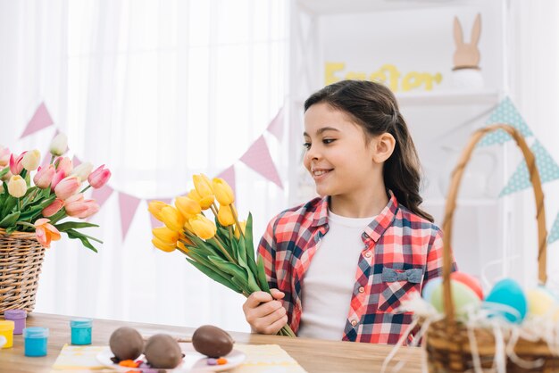 Portret dziewczyna patrzeje żółtych tulipanowych kwiaty na Easter dniu