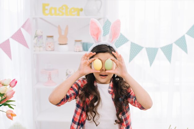 Portret dziewczyna trzyma Easter jajka przed jej oczami na Easter dniu w domu