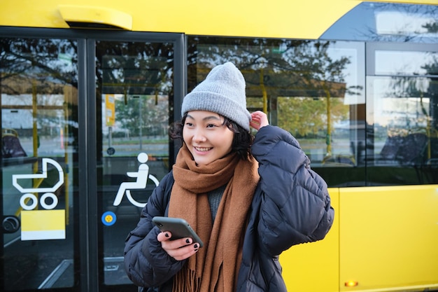 Portret dziewczyny stojącej w pobliżu autobusu na przystanku czekającej na rozkład jazdy transportu publicznego na sm