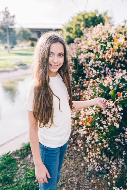 Bezpłatne zdjęcie portret dziewczyny trzyma kwiaty na roślinie w parku