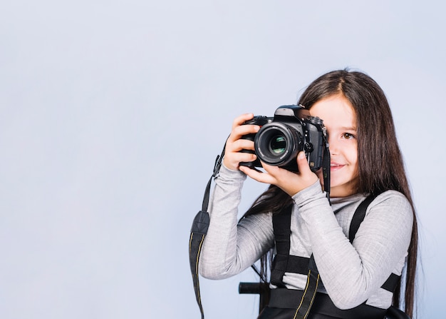 Portret fotograf zakrywa jej twarz z kamerą przeciw białemu tłu