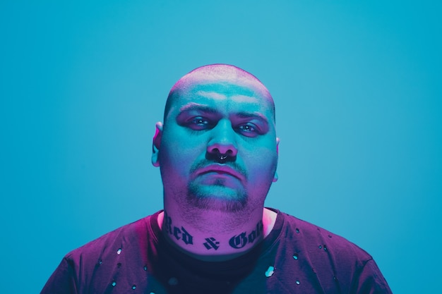 Portret hipstera z kolorowym neonowym światłem na niebieskim tle