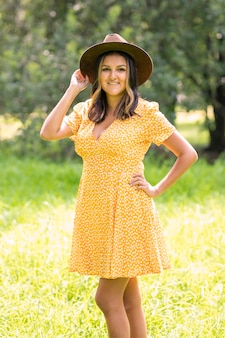 Portret hiszpanki z meksyku, ubranej w żółtą sukienkę i kapelusz, na tle drzew.