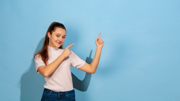 Portret kaukaski teen girl wyizolowanych w niebieskim studio