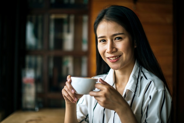 Portret kobiety azjatykci ono uśmiecha się relaksuje w sklep z kawą kawiarni