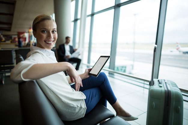Portret kobiety dojeżdżających z cyfrowego tabletu, siedząc w poczekalni