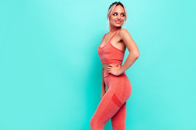 Portret kobiety fitness w różowej odzieży sportowej Młody piękny model z idealnym ciałemKobieta pozuje blisko ściany w studioWesoły i szczęśliwy Rozciąganie się przed treningiem