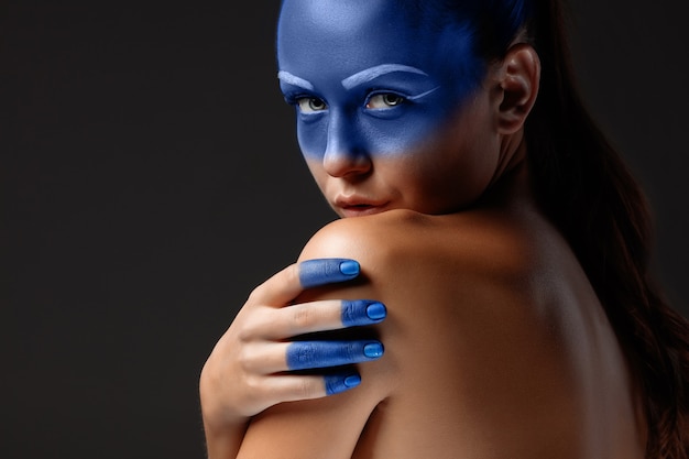 Portret kobiety, która pozuje pokryta niebieską farbą