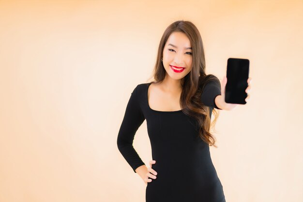 Portret kobiety pięknego młodego azjatykciego uśmiechu szczęśliwego use mądrze telefon komórkowy