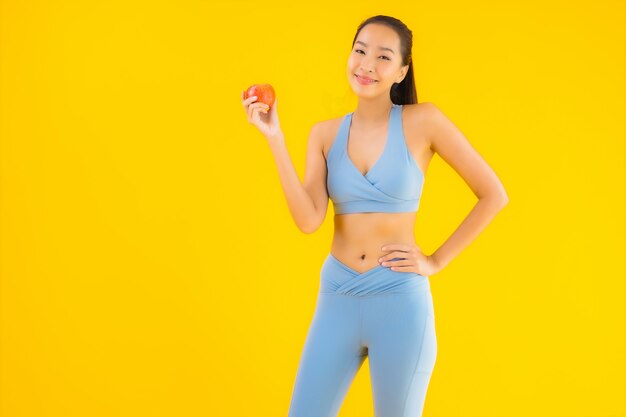 Portret kobiety piękny młody azjatykci odzieży sportwear przygotowywający dla ćwiczenia na kolorze żółtym