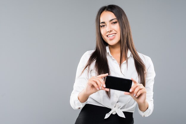 Portret kobiety podekscytowany młody biznes wskazując pusty ekran telefonu komórkowego na białym tle