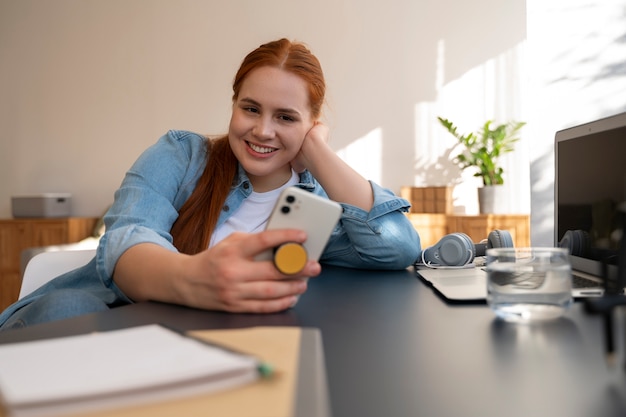 Bezpłatne zdjęcie portret kobiety używającej smartfona w domu z gniazdem pop