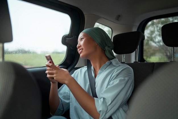 Portret kobiety z rakiem w samochodzie ze smartfonem