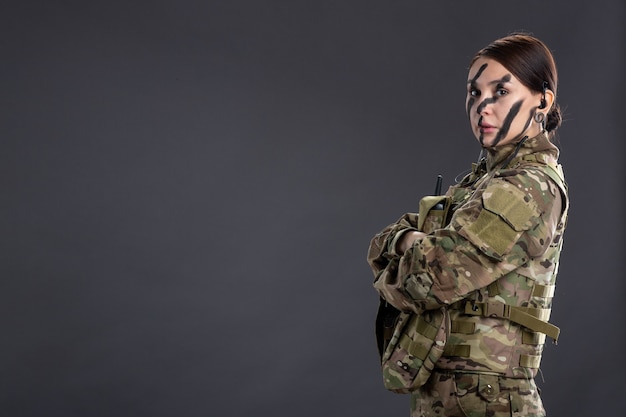 Portret kobiety-żołnierza w kamuflażu na ciemnej ścianie