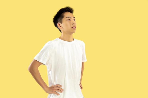 Portret koreańskiego młodzieńca. Model męski w białej koszuli. Stojąc i patrząc. Pojęcie ludzkich emocji, wyraz twarzy. Przedni widok. Modne kolory.