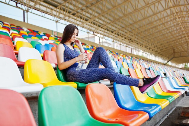 Portret ładnej kobiety w sportowej siedzącej i pitnej wodzie na stadionie