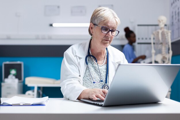 Portret lekarza ze stetoskopem za pomocą laptopa do pracy w opiece zdrowotnej w klinice. Kobieta lekarz pracujący z komputerem i technologią, aby przeprowadzić analizę leczenia na receptę do badania.