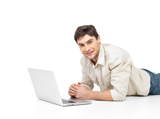 Portret leżącego udanego szczęśliwego człowieka z laptopem na białym tle.