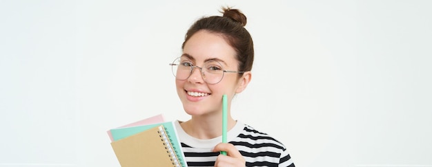 Bezpłatne zdjęcie portret mądrej dziewczyny w okularach nauczyciel trzymający długopis i zeszyty uczeń nosi swoje notatki domowe