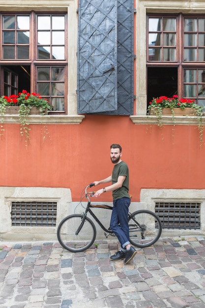 Portret męski cyklista z bicyklem przed budynkiem