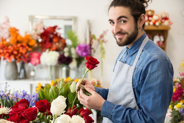 Portret męski mienie czerwieni róży kwiat w ręce patrzeje kamera