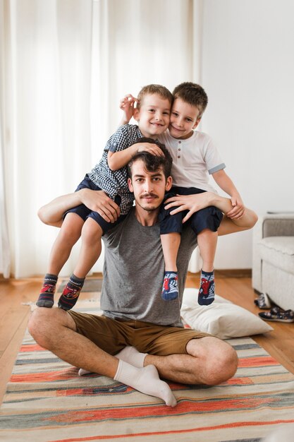 Portret mężczyzna niesie jego dwa syna na ramieniu w domu