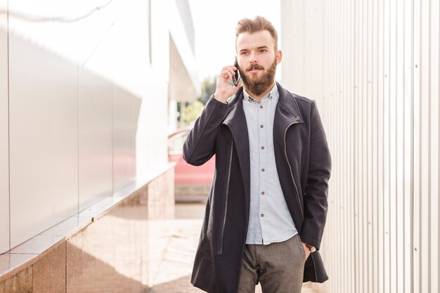 Portret mężczyzna opowiada na telefonie komórkowym w czarnej kurtce