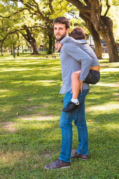 Portret mężczyzny, dając przejażdżkę piggyback w parku