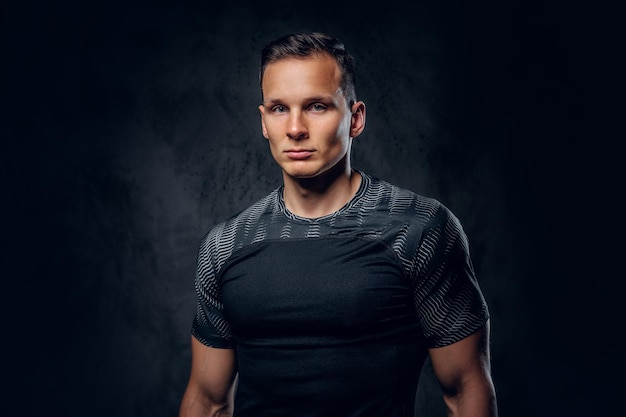 Portret mężczyzny fitness lekkoatletycznego ubrany w odzież sportową na szarym tle winiety.