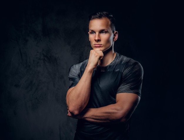 Portret mężczyzny fitness lekkoatletycznego ubrany w odzież sportową na szarym tle winiety.