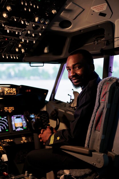 Portret mężczyzny lotnika siedzącego w kokpicie samolotu gotowego do lotu, za pomocą przycisków nawigacyjnych panelu sterowania i przycisków poleceń na desce rozdzielczej. Pilotuj samolot z kompasem na przedniej szybie i radarem.