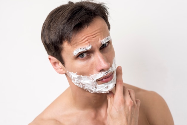 Portret mężczyzny myślenia z pianki do golenia na twarzy