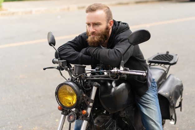 Bezpłatne zdjęcie portret mężczyzny siedzącego na motorze z melancholijny wypowiedzi
