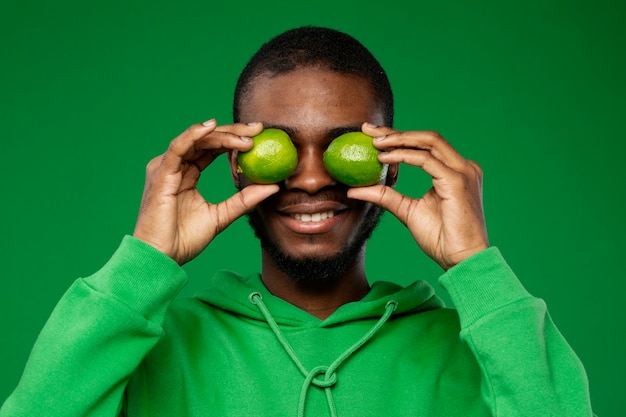 Bezpłatne zdjęcie portret mężczyzny trzymającego limonki nad oczami