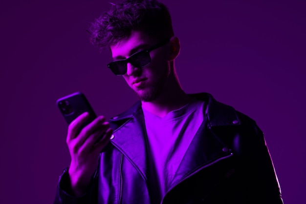 Portret mężczyzny w okularach uważnie patrząc na wiadomość czytanie telefonu na białym tle na niebieskim tle w neony Pojęcie ludzkich emocji wyraz twarzy styl życia Skopiuj miejsce na reklamę