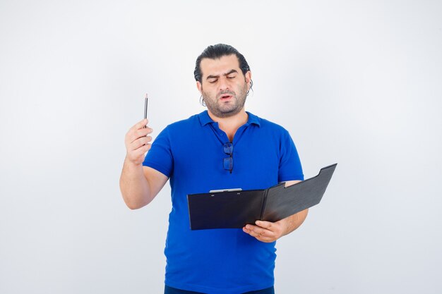 Portret mężczyzny w średnim wieku ze schowkiem, trzymając ołówek w koszulce polo