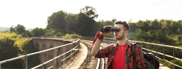 Portret mężczyzny z plecakiem patrząc przez lornetkę