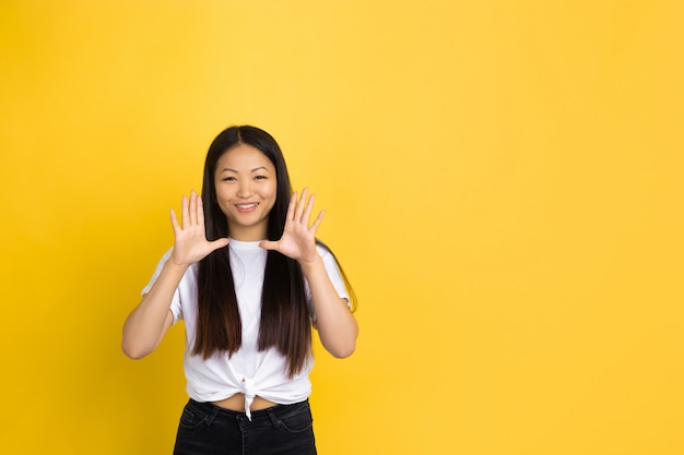 Portret młoda azjatykcia kobieta odizolowywająca na kolor żółty ścianie