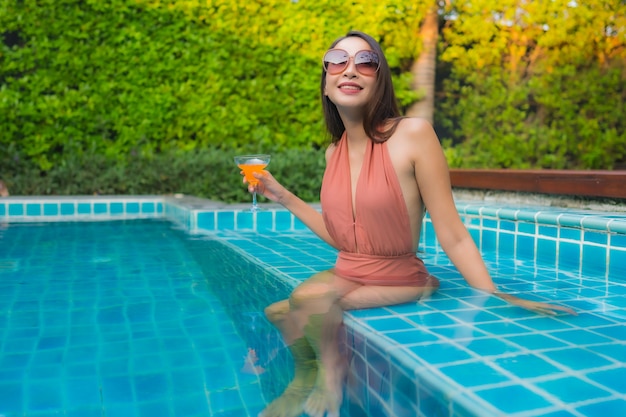 Portret młoda azjatykcia kobieta relaksuje szczęśliwego uśmiech wokoło pływackiego basenu w hotelu