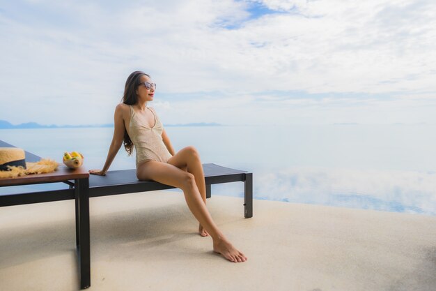 Portret młoda azjatykcia kobieta relaksuje uśmiech szczęśliwego wokoło pływackiego basenu w hotelu i kurorcie