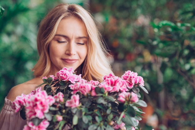 Portret młoda blondynki kobieta wącha różowego kwiatu