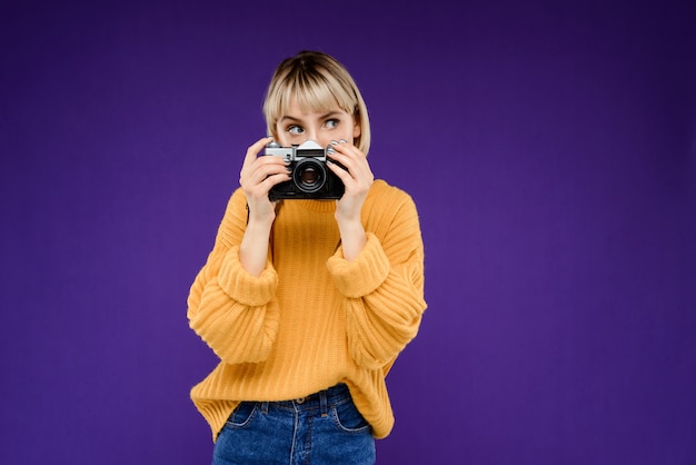 Bezpłatne zdjęcie portret młoda kobieta z kamerą nad purpury ścianą