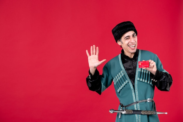 Portret Młodego Azerskiego Mężczyzny W Tradycyjnym Stroju, Trzymającego Kartę Kredytową Na Czerwono
