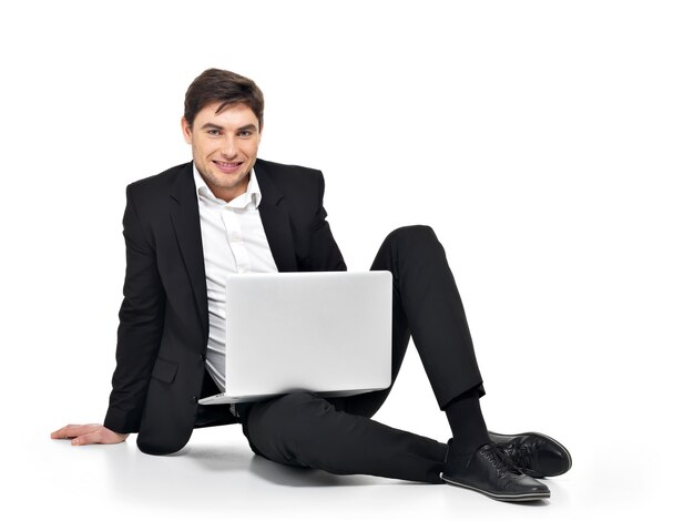 Portret młodego biznesmena szczęśliwy pracuje na laptopie na białym tle.