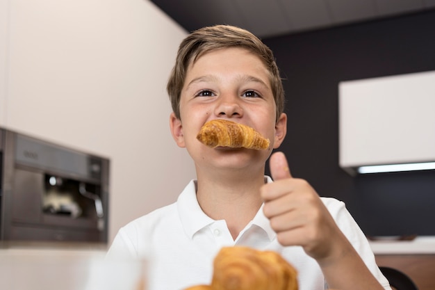 Bezpłatne zdjęcie portret młodego chłopca, jedzenie rogalików