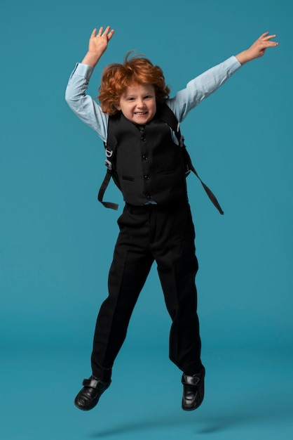 Bezpłatne zdjęcie portret młodego chłopca ucznia w mundurku szkolnym, skoków w powietrzu
